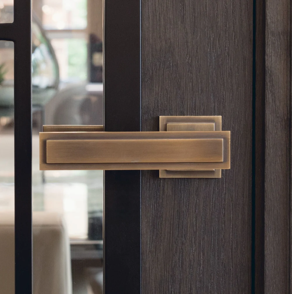 Luxury external door handles in a bronze finish fitted to a dark wooden door.