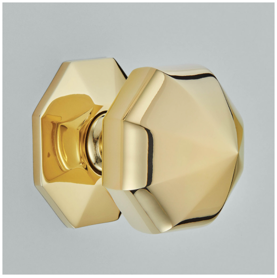 Polished brass Georgian door furniture featuring a faceted door knob and matching decorative backplate.
