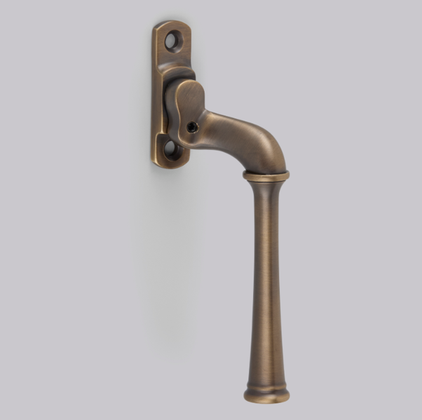 Traditional Window Hardware featuring an antique brass casement window handle with a long decorative lever.